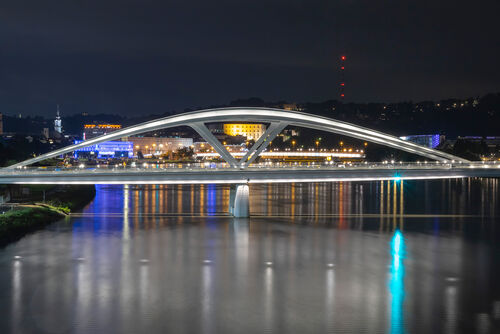 Neue Linzer Brücke, dahinter Linz in der Nacht.