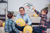 LR Michael Lindner sitzt mit seinen beiden Söhnen Samuel und Thomas am Boden. Dazwischen befinden sich Luftballone und eine Sprechblase bei LR Lindner: Kinde haben Rechte!
