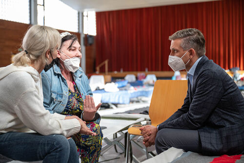 Landesrat Dr. Wolfgang Hattmannsdorfer sitzt in einer Notschlafstelle in Linz zwei ukrainischen Frauen gegenüber und unterhält sich mit ihnen.