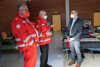 Landesrat Dr. Wolfgang Hattmannsdorfer steht gegenüber von zwei Mitarbeitern des Roten Kreuzes in einer Linzer Notschlafstelle und unterhält sich mit ihnen. 
