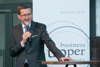 Wirtschafts-Landesrat Markus Achleitner steht bei einem Stehtisch und hält ein Mikrofon in der Hand. 