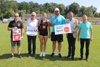 Richard Gierlinger, Hubert Lang, Patricia Madl, Lukas Weißhaidinger und Landesrat Markus Achleitner mit Tafel mit Beschriftung Infrastrukturoffensive Sport Oberösterreich, sowie Franz Schiefermair stehen nebeneinander auf einem Sportrasen, 