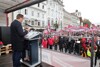 Landesrat Markus Achleitner auf der Bühne an einem Rednerpult mit Mikrofonen, Menschenmenge vor der Bühne 