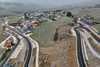 Luftbild einer hügeligen Landschaft mit Ortschaft und frisch asphaltierten Straßen