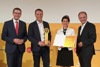 Landesrat Markus Achleitner, Ing. Peter Fischerleitner mit Preis, Mag.a Karoline Fischerleitner mit Urkunde und DI Dr. Gerhard Dell stehen nebeneinander, dahinter auf einer Wand Logos des Energiesparverbandes, Solar Champion 2021 und Tips