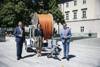 Landeshauptmann Mag. Thomas Stelzer, Telekom-Ministerin Elisabeth Köstinger und Wirtschafts-Landesrat Markus Achleitner vor dem Landhaus in Linz mit einer Breitband-Kabelrolle.