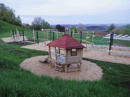 Spielgeräte für Kinder auf einer grünen Wiese auf einem Hang