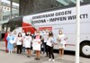 Gruppenfoto mit 13 Personen vor einem Corona-Impfbus, alle mit Mund-Nasen-Schutz bzw. FFP2-Maske, alle halten Plakate und T-Shirts mit Beschriftung Geimpft, das bessere G!