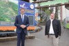 – Wirtschafts- und Tourismus-Landesrat Markus Achleitner und Michael Eibl, Bürgermeister von Windischgarsten stehen vor einer Tafel mit der Aufschrift „Wurbauerkogel“, im Hintergrund der Zugang zum Wurbauerkogel.