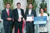 Landesrat Markus Achleitner, Stefan Schaffelhofer mit Preis, Robert Prückl mit Urkunde und Stefanie Christina Huber mit Preis stehen nebeneinander, hinter ihnen mannshohe Blumengestecke