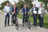 Dipl.-BW Friedrich Kaindlstorfer, Landesrat Markus Achleitner auf einem E-Bike, Landesrat Jochen Danninger auf einem E-Bike, Mag. Michael Duscher und Mag. Bernhard Schröder stehen nebeneinander auf einem Weg im Linzer Donaupark 