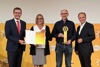 Landesrat Markus Achleitner und Judith Steininger halten gemeinsam eine Urkunde, Alfred Steininger mit Preis und DI Dr. Gerhard Dell stehen nebeneinander, dahinter auf einer Wand Logos des Energiesparverbandes, von Solar Champion 2021 und  Tips 