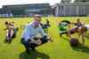 Landesrat Markus Achleitner auf einem Fußballplatz in Hockstellung, er deutet mit beiden Daumen nach oben, hinter ihm Kinder, die mit großen Bällen trainieren