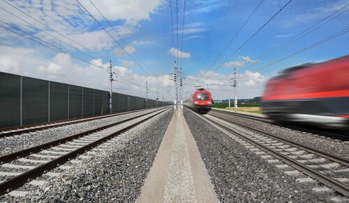 Viergleisige Westbahnstrecke auf der gerade zwei rote Züge mit hoher Geschwindigkeit fahren