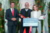 Landesrat Markus Achleitner, Prof. Wolfgang Schöfberger mit Preis und Alexandra Halouska mit Urkunde und Preis stehen nebeneinander, hinter ihnen mannshohe Blumengestecke