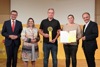 Landesrat Markus Achleitner, Alexandra Mittermayr, Stefan Brandstetter mit Preis, Johanna Brandstetter mit Urkunde und DI Dr. Gerhard Dell stehen nebeneinander, dahinter auf einer Wand Logos des Energiesparverbandes, Solar Champion 2021, OÖ Nachrichten und Oberösterreich-Logo