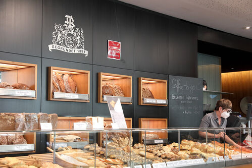 Bäckerei-Geschäft, hinter der Theke Brot und Gebäck, Verkäuferin, an der Wand ein Schild mit Beschriftung Ama Genuss Region