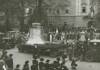 Große Glocke auf einem mit Zweigen und Blumen geschmückten Tieflader, der von einem LKW gezogen wird, hunderte Zuschauerinnen und Zuschauer auf der Promenade vor dem Linzer Landhaus, Fahnen, Fotografen, Musikkapelle 