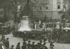 Große Glocke auf einem mit Zweigen und Blumen geschmückten Tieflader, der von einem LKW gezogen wird, hunderte Zuschauerinnen und Zuschauer auf der Promenade vor dem Linzer Landhaus, Fahnen, Fotografen, Musikkapelle 