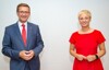 Wirtschafts-Landesrat Markus Achleitner und WKOÖ-Präsidentin Mag.a Doris Hummer stehen nebeneinander vor einem grauen Hintergrund.