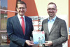 Landesrat Markus Achleitner und Mag. Manfred Luger stehen nebeneinander und halten gemeinsam eine Broschüre in Händen, auf dem Titelblatt die Beschriftung Arbeitsplatz OÖ 2030 und Oberösterreich-Logo