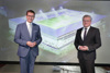 Landesrat Markus Achleitner und Bürgermeister Klaus Luger stehen nebeneinander vor einer großen Leinwand, auf die das Modell des Stadion projiziert ist