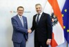 Landesrat Achleitner schüttelt Bundeskanzler Nehammer die Hand vor der Österreich- und der EU-Flagge