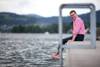 Mann mit Brille sitzt barfuß am Ufer eines Sees