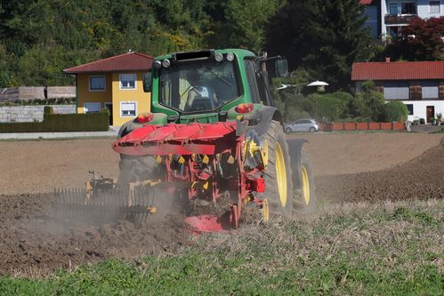 Bauer in einem Traktor beim Ackern auf einem Feld