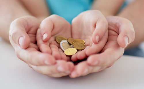 Hände von Erwachsenem und Kind halten Münzen