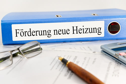 Brille, Füllfeder und ein blauer Ordner mit der Aufschrift „Förderung neue Heizung“