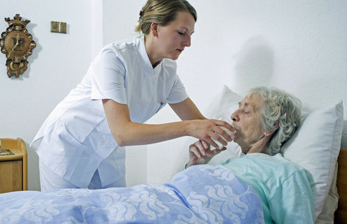 Eine junge Pflegerin betreut eine sehr alte Dame.