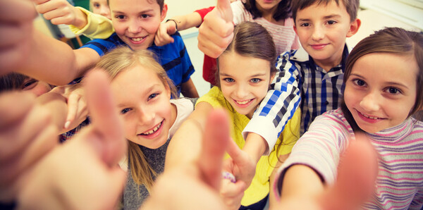 Fröhliche Schülerinnen und Schüler strecken ihre Daumen nach oben