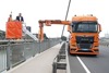 Landesrat Mag. Günther Steinkellner und eine zweite Person auf dem Hubarm eines Spezial-Lastkraftfahrzeuges auf einer Brücke