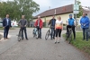 Florian Hackl, Christian Roithmeier mit Fahrrad, Dipl.-Ing. Christian Dick mit Fahrrad, Karl Velechovsky mit Fahrrad, Dr.in Sabine Naderer-Jelinek in Fahrradbekleidung, Landesrat Mag. Günther Steinkellner mit Fahrrad und Stadtrat Prof. Mag. Michael Täubel auf einem Radweg, im Hintergrund ein Wegweiser für einen Radweg, Straße, Auto und ein Gebäude