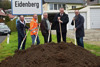 Markus Haslehner, Konrad Leitner, Adi Hinterhölzl, Landesrat Mag. Günther Steinkellner und Günter Pröller, alle mit Spaten, stehen nebeneinander hinter einem Erdhügel, im Hintergrund Ortsschild von Eidenberg