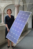 Landesrätin Michaela Langer-Weninger steht mit einem Solarpanel in Händen in einem Arkadengang