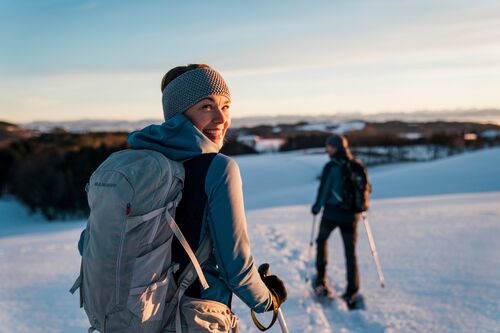Zwei Personen beim Schneeschuhwandern in hügeliger winterlicher Landschaft