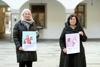 Birgit Mayr-Mauhart und Landesrätin Birgit Gerstorfer stehen nebeneinander im Hof des Ursulinenhof-Gebäudes, beide halten jeweils ein Poster zur Kampagne in Händen