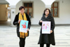 Theresia Schlöglmann und Landesrätin Birgit Gerstorfer stehen nebeneinander im Hof des Ursulinenhof-Gebäudes, beide halten jeweils ein Poster zur Kampagne in Händen