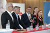 Bei der Pressekonferenz: Wolfgang Gotschke, Vize-Kanzler und Sportminister Werner Kogler, Landesrat Markus Achleitner sprechend in ein Mikrofon, Sofia Polcanova und Anastasia Sterner stehen nebeneinander an einem langen Pult