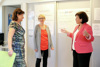 Judith Rameseder, Christine Lasinger und Landesrätin Birgit Gerstorfer im Gespräch in einem Büroraum, an der Wand hängen selbstgeschriebene Poster mit Beschriftung zB Workshops, Frauen Job Welt