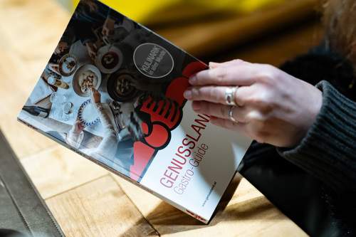 Eine Frau blättert im neuen Genussland Gastro-Guide. 