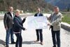 Rudolf Kroiß, Nicole Eder, Gerhard Kaniak und Landesrat Günther Steinkellner auf einer Straßenbaustelle, gemeinsam halten sie einen Bauplan in Händen