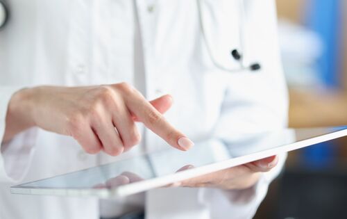 Ärztin zeigt mit Finger auf ein Tablet