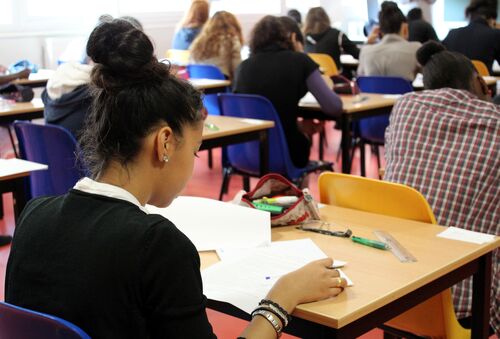 Junge Menschen an einzelnen Tischen lernen in einem Klassenzimmer