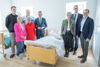 Eine Gruppe von sieben Personen steht in einem Übungs-Krankenzimmer um ein Krankenbett, darin liegt eine lebensgroße Puppe