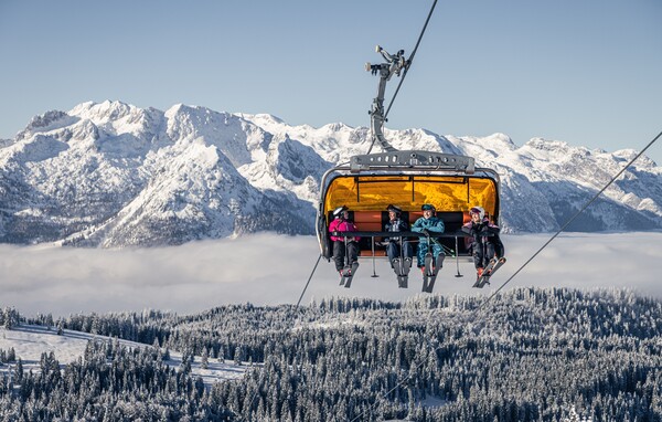 Schifahrer auf einem 6er Sessellift in der Skiregion Dachstein West