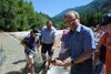 Landesrat Ing. Wolfgang Klinger hält einen Fisch in der Hand, im Hintergrund Kinder mit Netz, im dem sich ein Fisch befindet