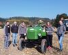 Fünf junge Frauen stehen auf einem Acker neben einem Traktor